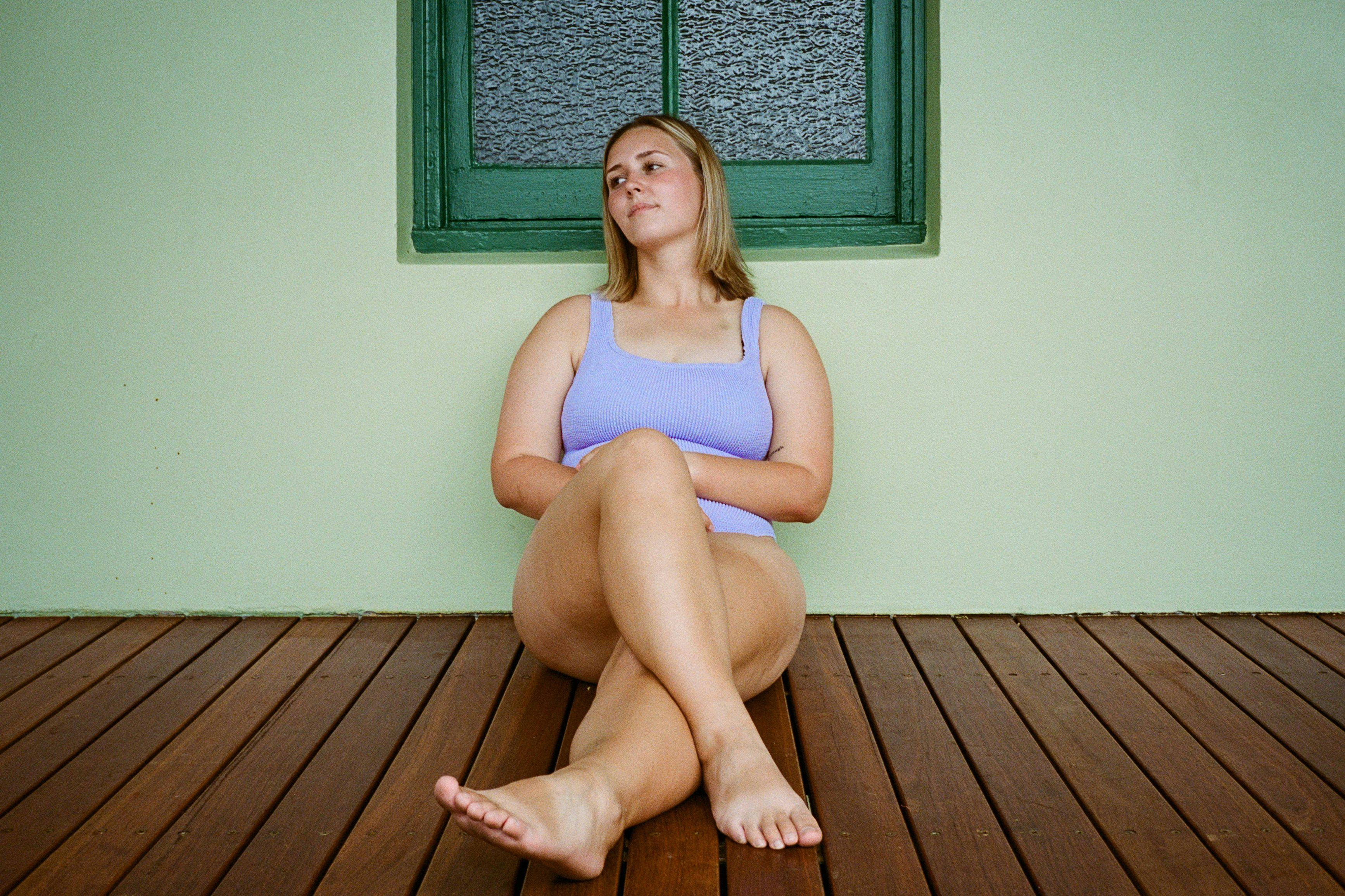 Piper sitting on a deck in a purple swimsuit.