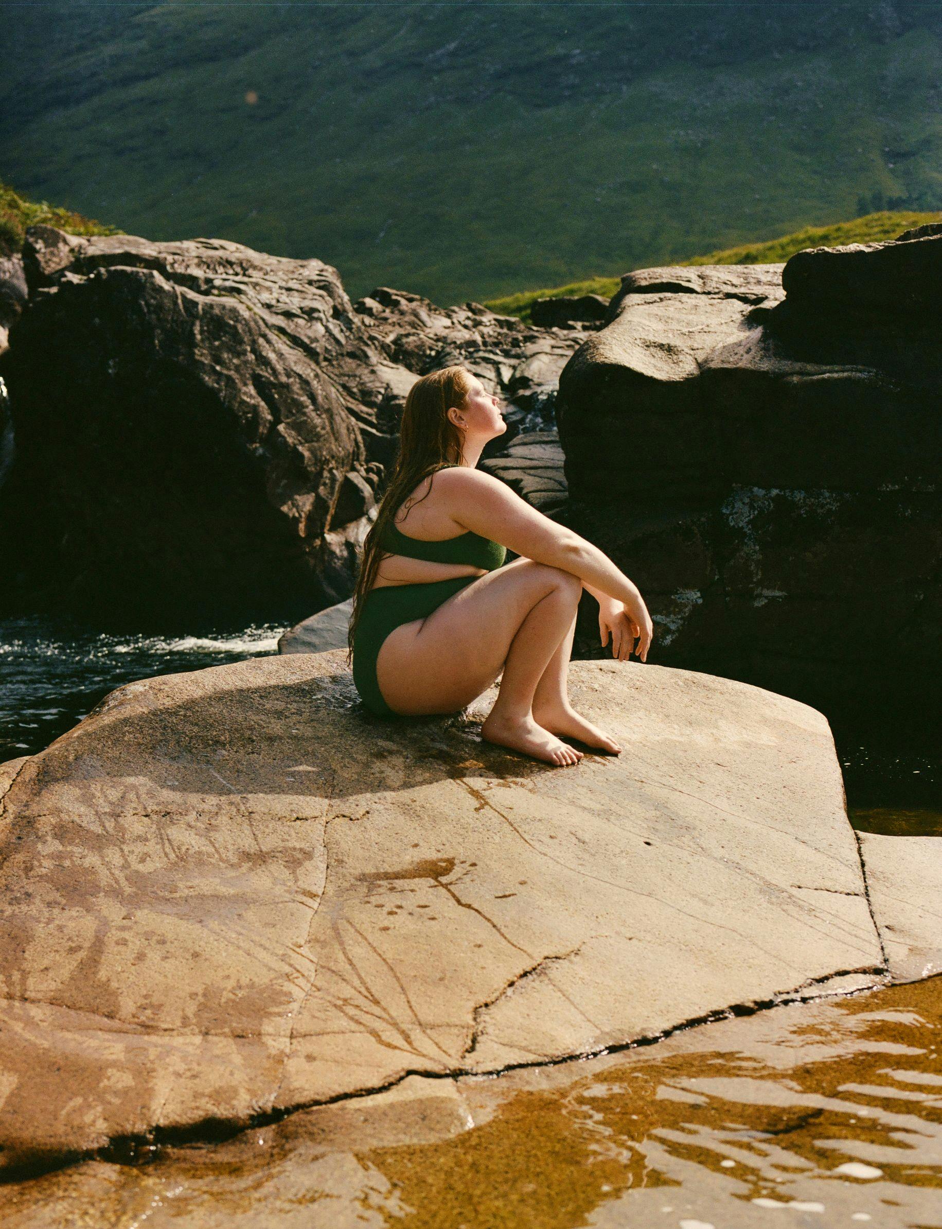 Thea sitting on rock by water