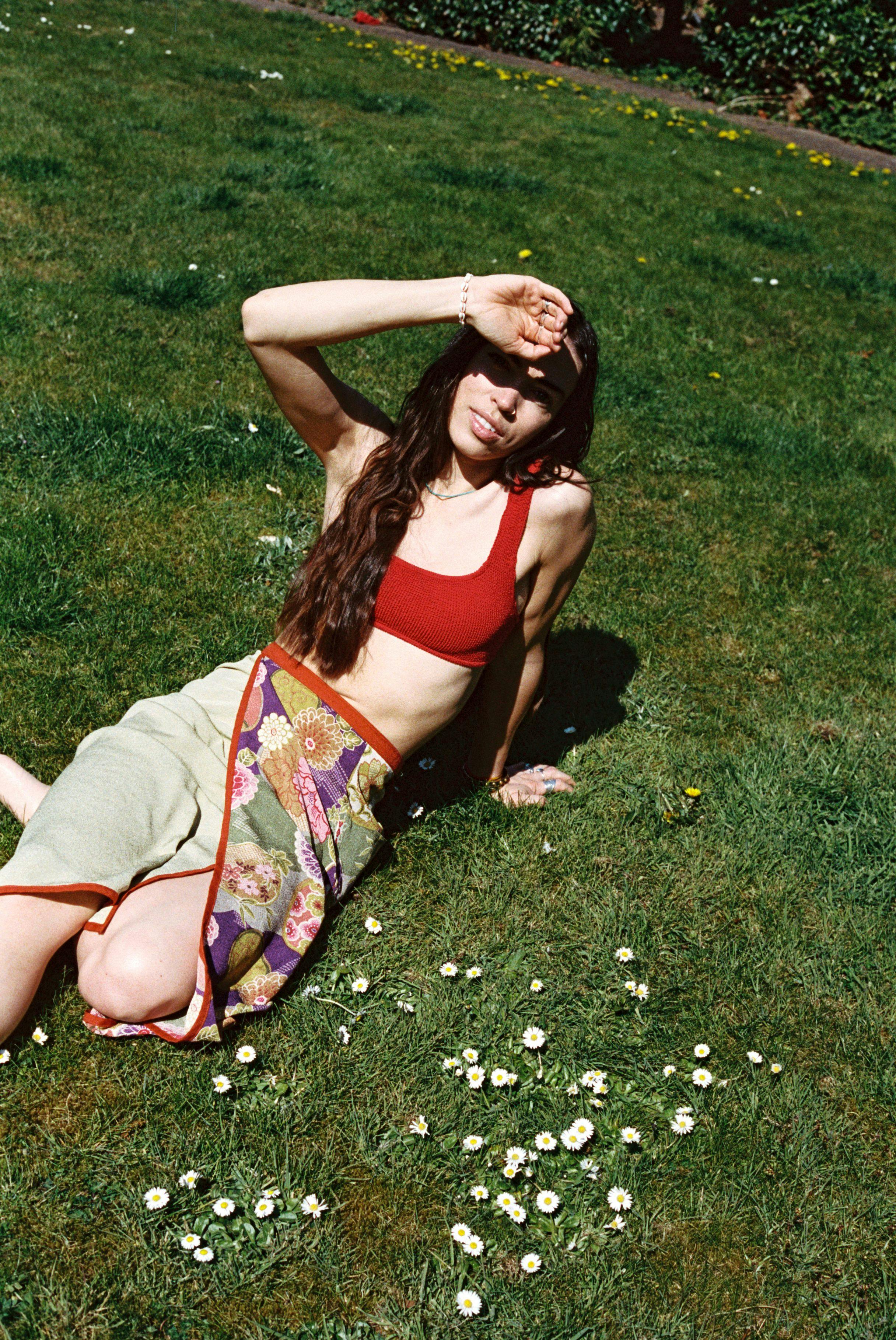 Jaz O'Hara in red bikini and skirt, lying on grass